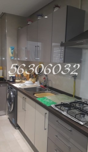 Cuisine moderne et bien équipée avec des armoires, un évier, une cuisinière et un lave-linge.